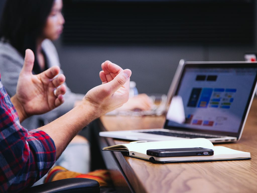 Hands of a person talking in front of a computer