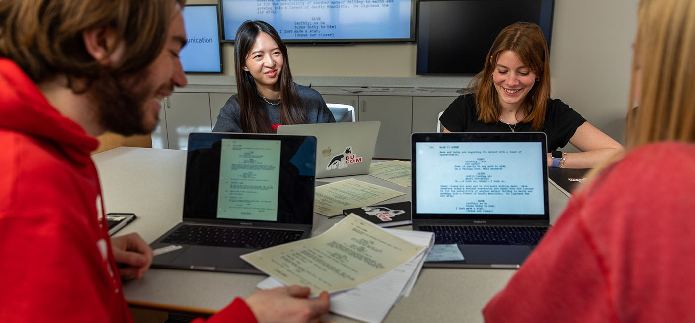 Student team seated at a table working on a script.