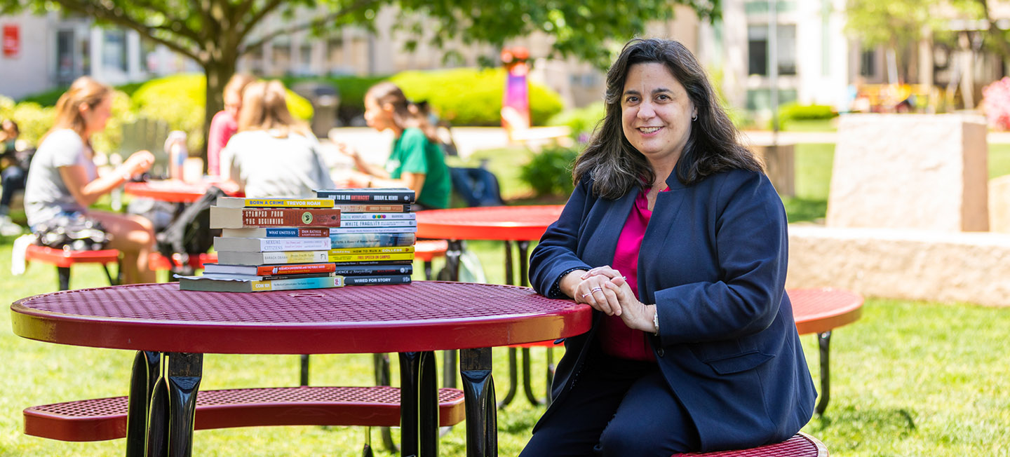 COM Dean Mariette DiChristina seated at table on COM Lawn.