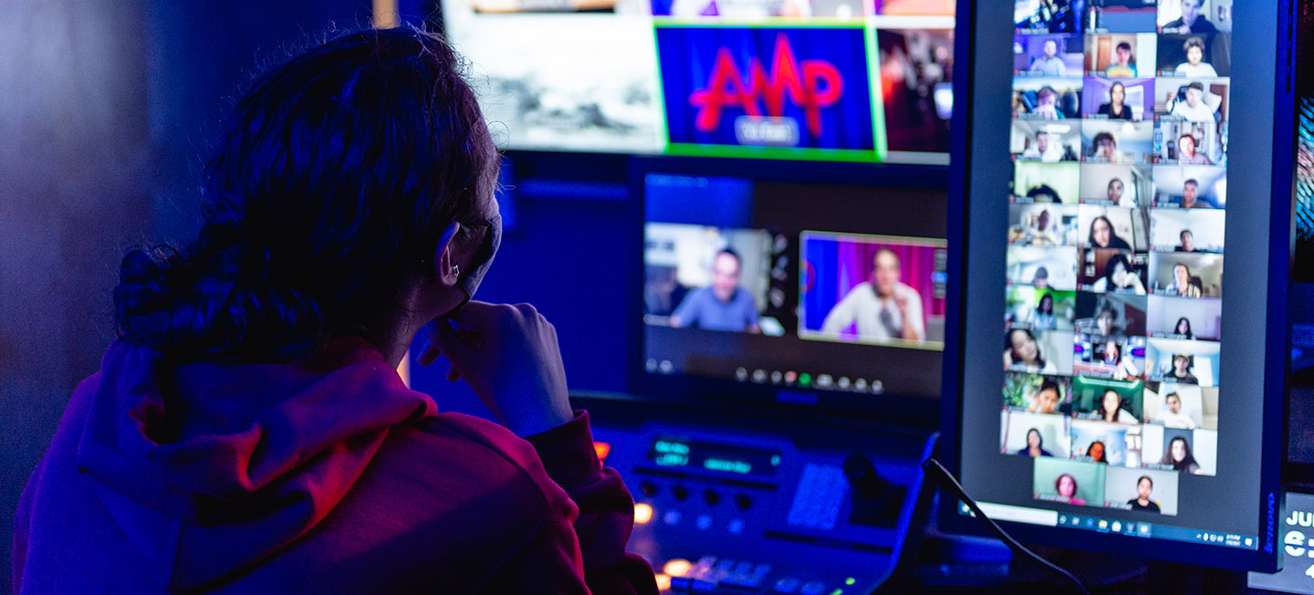 Photo from behind of woman directing television livestream from the control room.