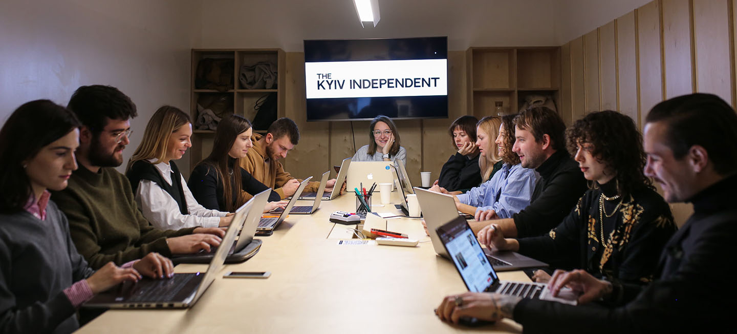 Group of journalists meeting around a long table.