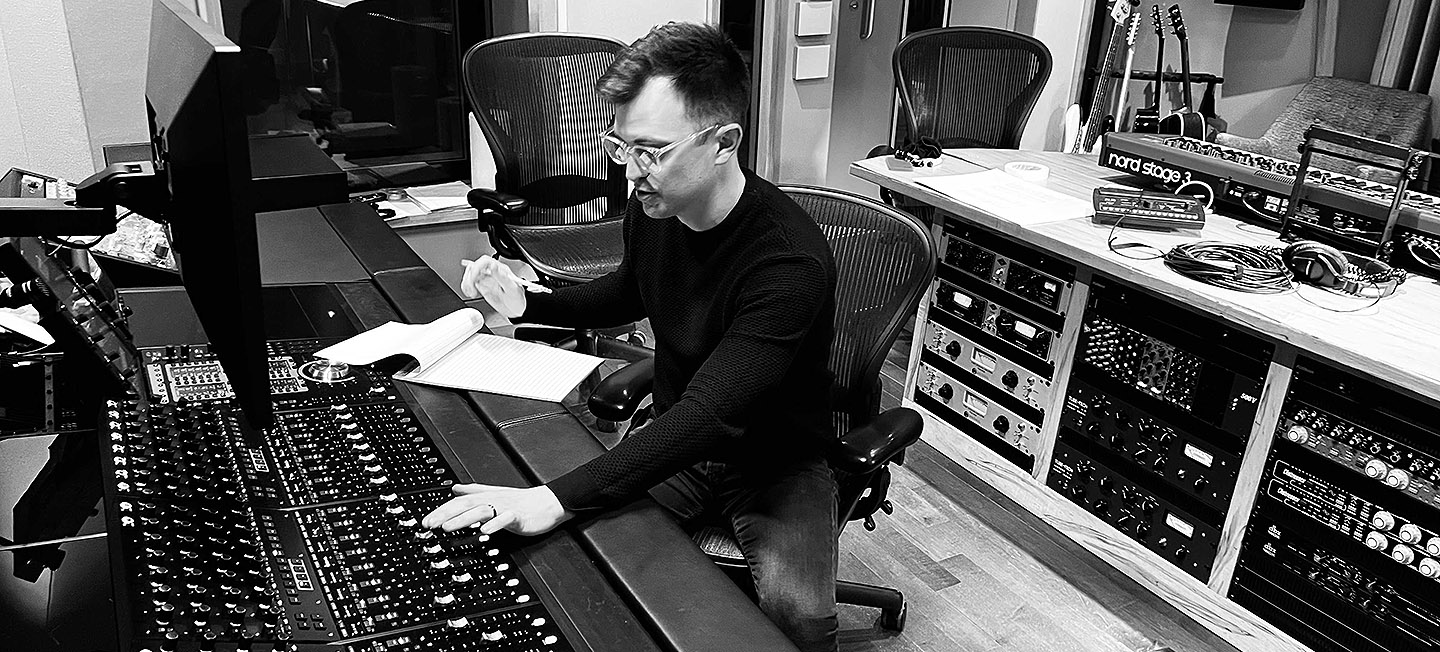 Alex Coutts sitting at the mixing board in a sound studio.