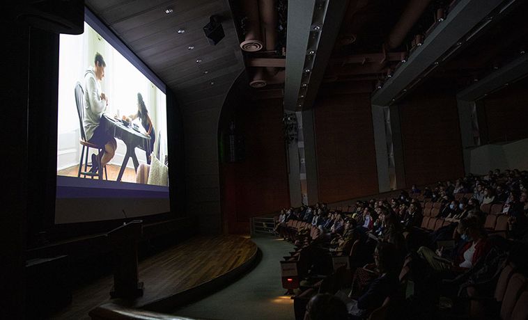 Crowd seated in a dark theater watching a film.