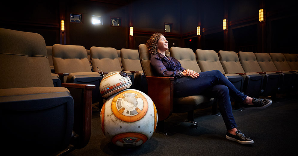 Janet Lewin sits in a theater with Star Wars droid BB-8.