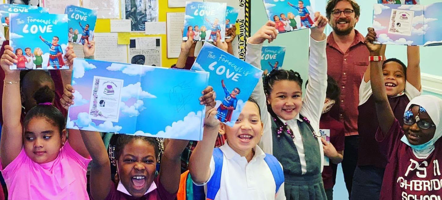 Group of young students smiling and holding up copies of a book titled "The Forecast Is Love."