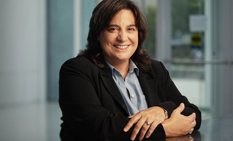 COM Dean Mariette DiChristina seated at a table with arms folded.