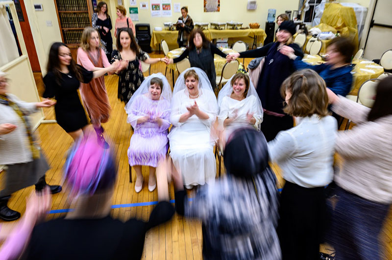 Three brides encircled by a ring of dancing women.