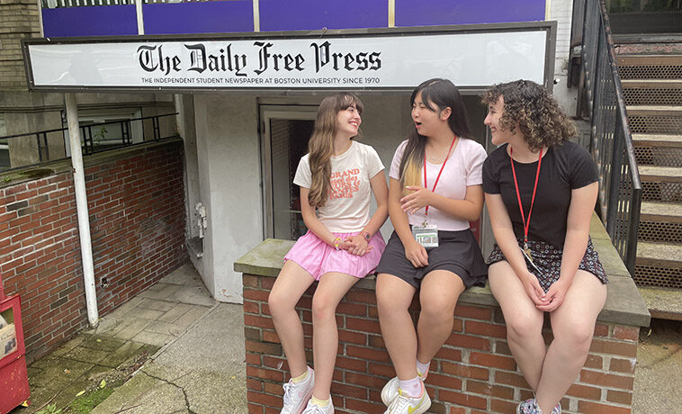 BU Summer Journalism Academy students sitting on a wall in front of the Daily Free Press office.