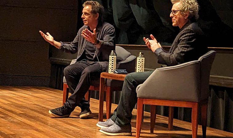 Ben Stiller gesturing to the crowd while seated next to Jeff Kahn.