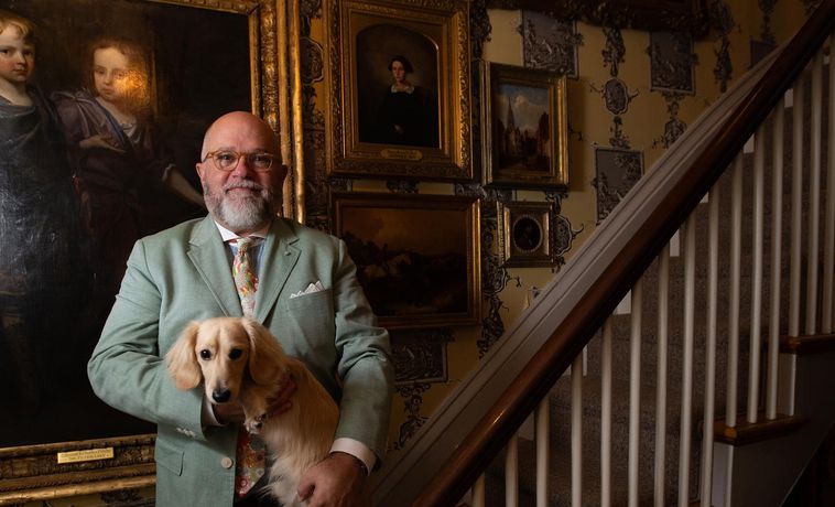 D. Brenton Simons in his home holding a dog