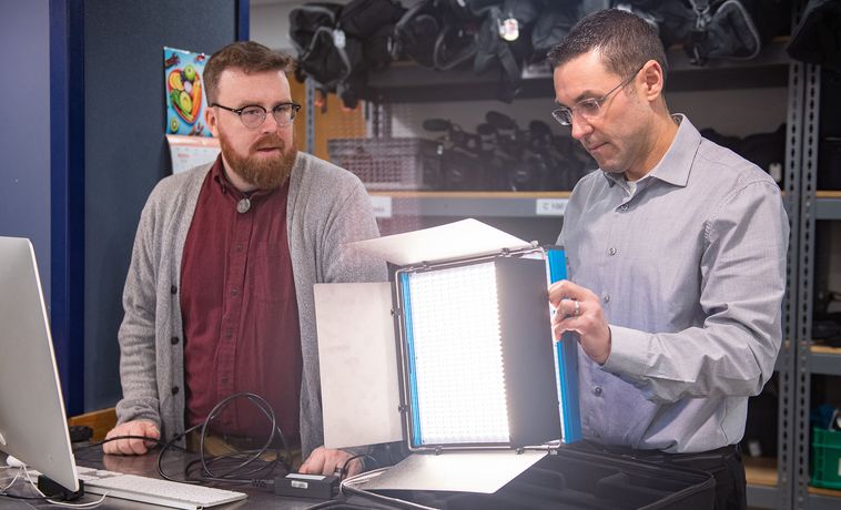 Douglas Cowell and Brad Fernandes test an LED light in the equipment room of COM Field Production Services.