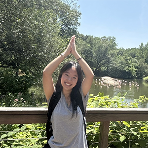 A joyful photo of Elaine Liu standing in front of a pond. 