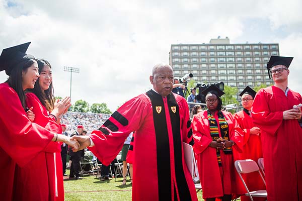 A female graduate shakes the hand of Congressman John Lewis as he processes by on Nickerson Field.