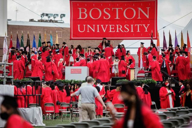 Students flood the stage to celebrate following the 2021 BU Commencement ceremony for undergraduate degrees.