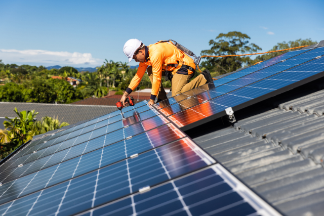 Worker installing solar panels on roof