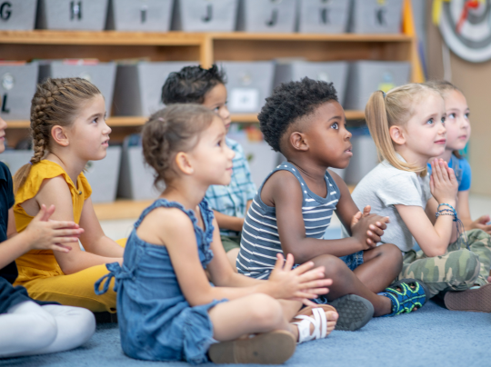 Group of preschoolers sitting on floor and listening attentively