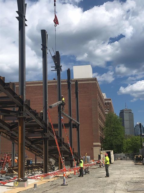 Ironworkers setting a steel beam in place for the 2nd-floor framing