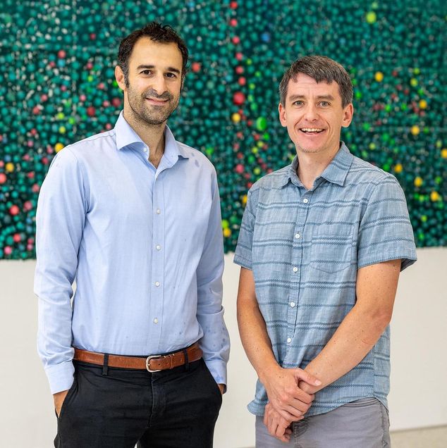 Two people smiling after one of them receives an award for their research