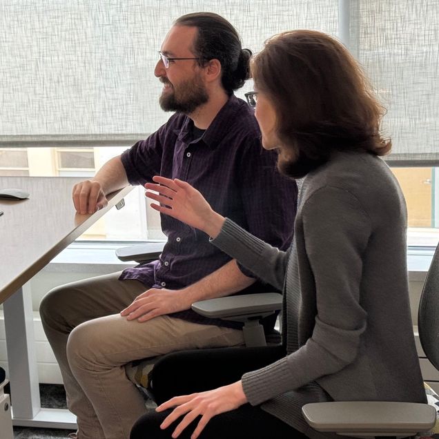 Two people sitting in front of a computer to examine a data visualization from a functional magnetic resonance imaging