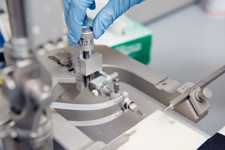 closeup of a hand adjusting settings on a microscope