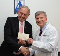 Alpha Omega President Adam Stabholz presents a check to Dean Jeffrey W. Hutter.