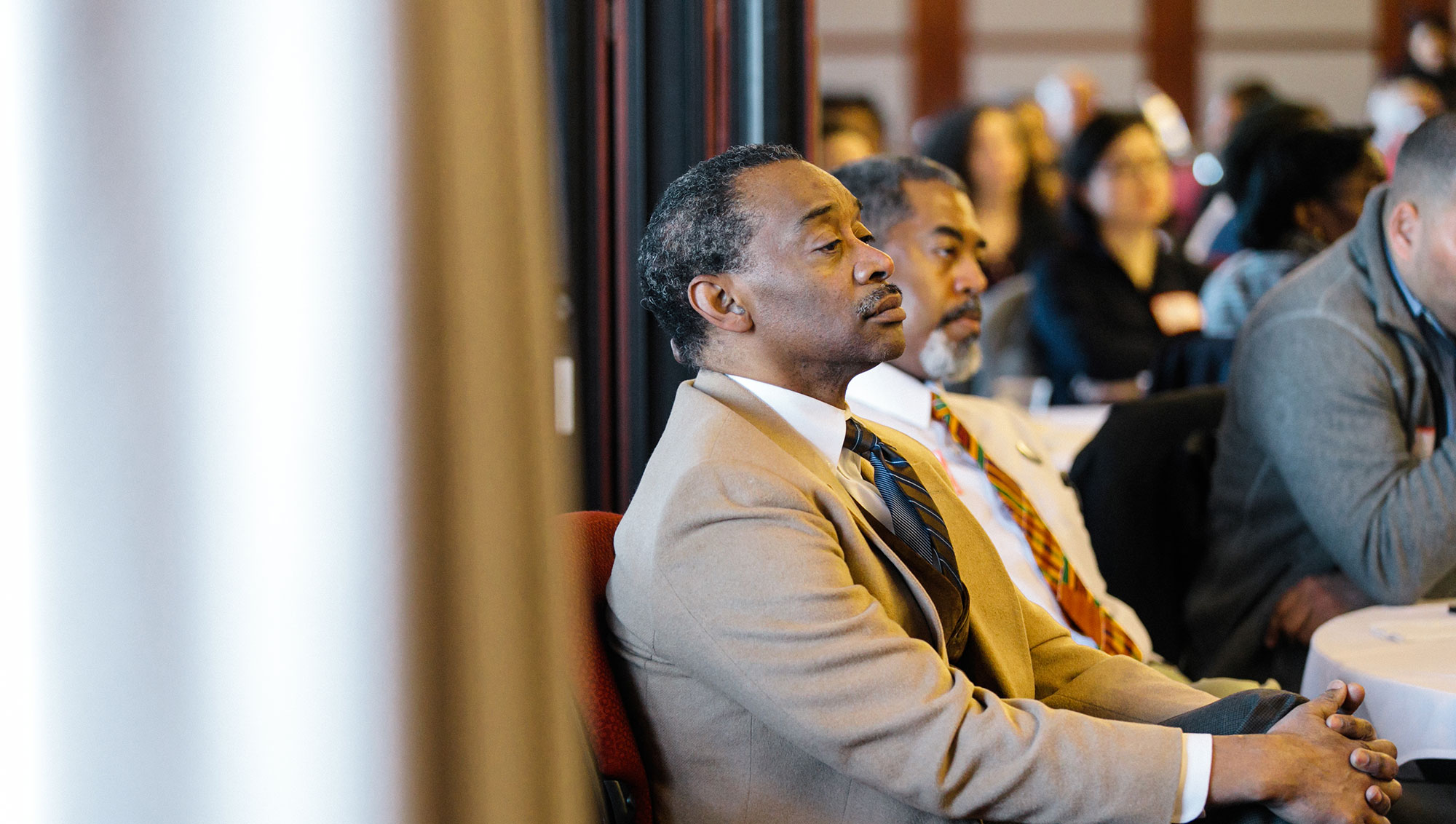 Male faculty members listening to a speaker