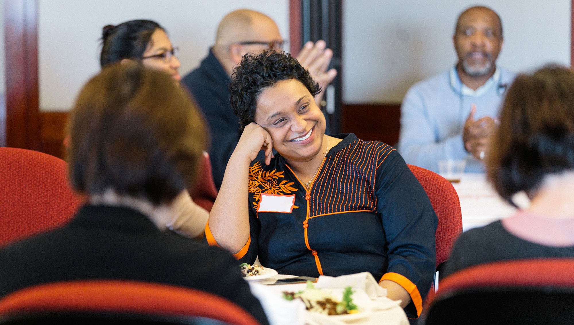 Woman sitting at a table at a Diversity & Inclusion event listening to a speaker