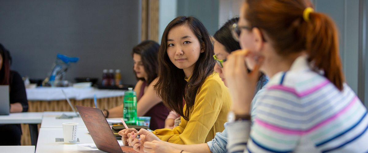 A diverse group of female graduate students working together in a classroom