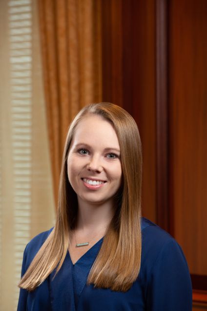 Photo of Abby Burmeister. They are wearing a blue blouse and a necklace.