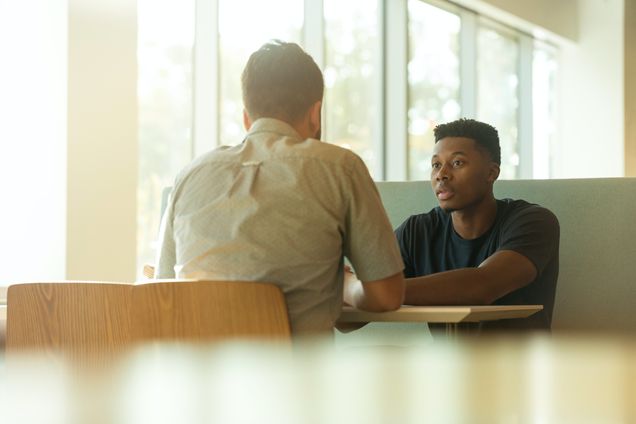 White man sitting across a table from a Black man