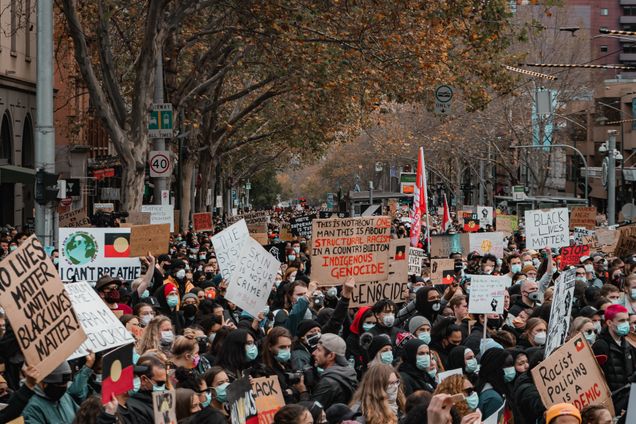 Group of people at protests holding a collection of signs protesting racism