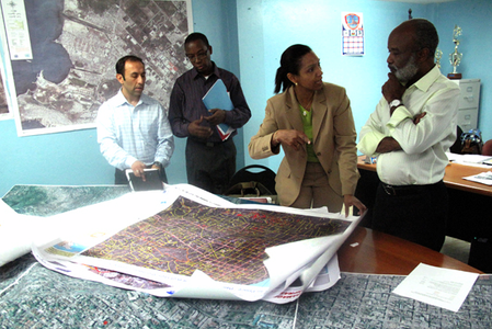BU’s Enrique Silva (from left), Jean Luciene Ligondé, and Elisabeth Coicou and Haitian President René Préval look over maps of Port-au-Prince brought to Haiti by the BU team.