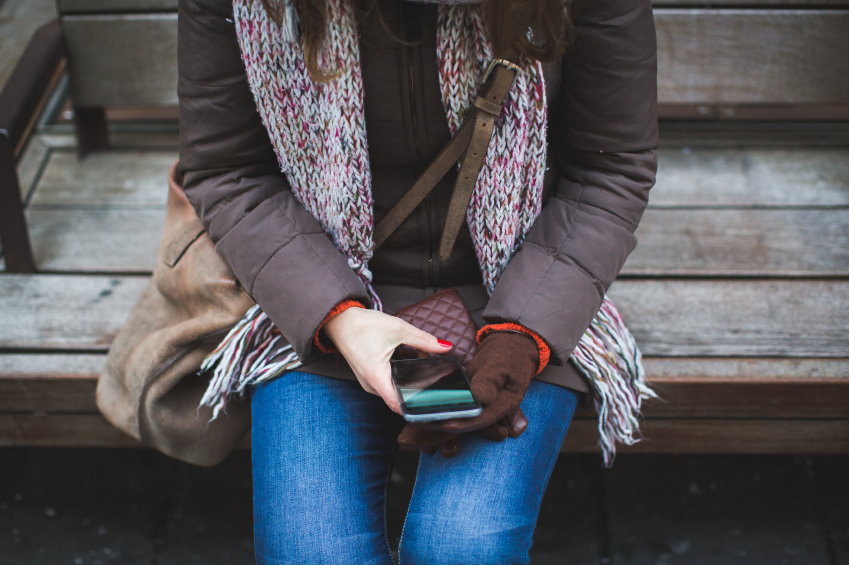 Lonely woman in scarf looking at smart phone