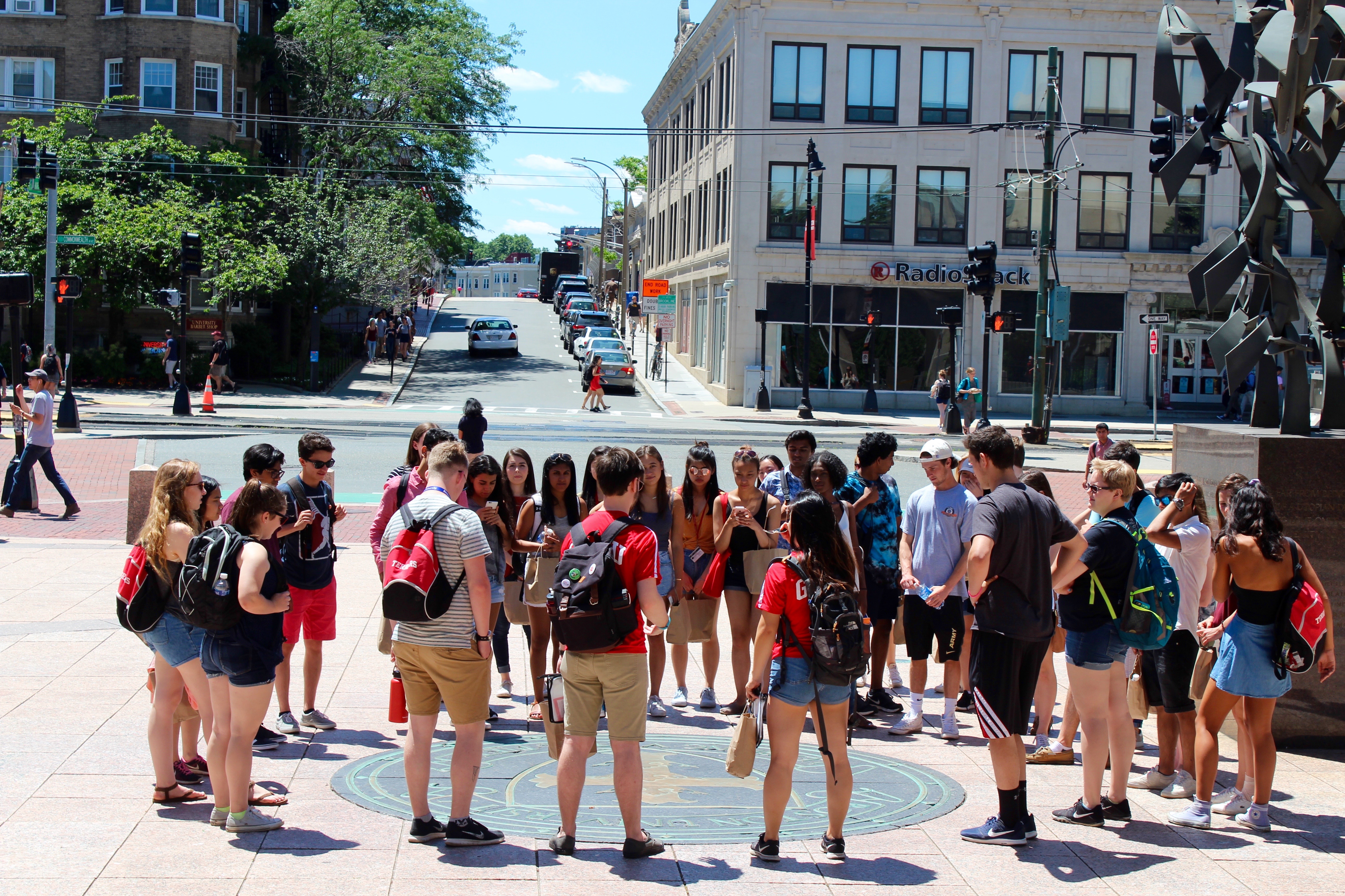 A group of students circles the BU Seal. 