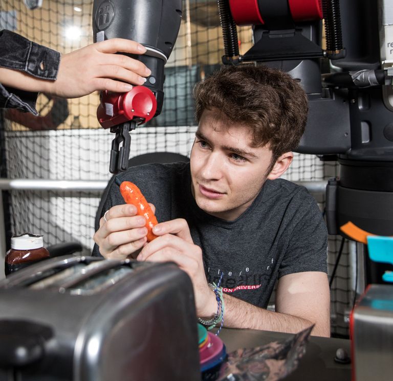 student working with a robot, preparing to book a hotdog