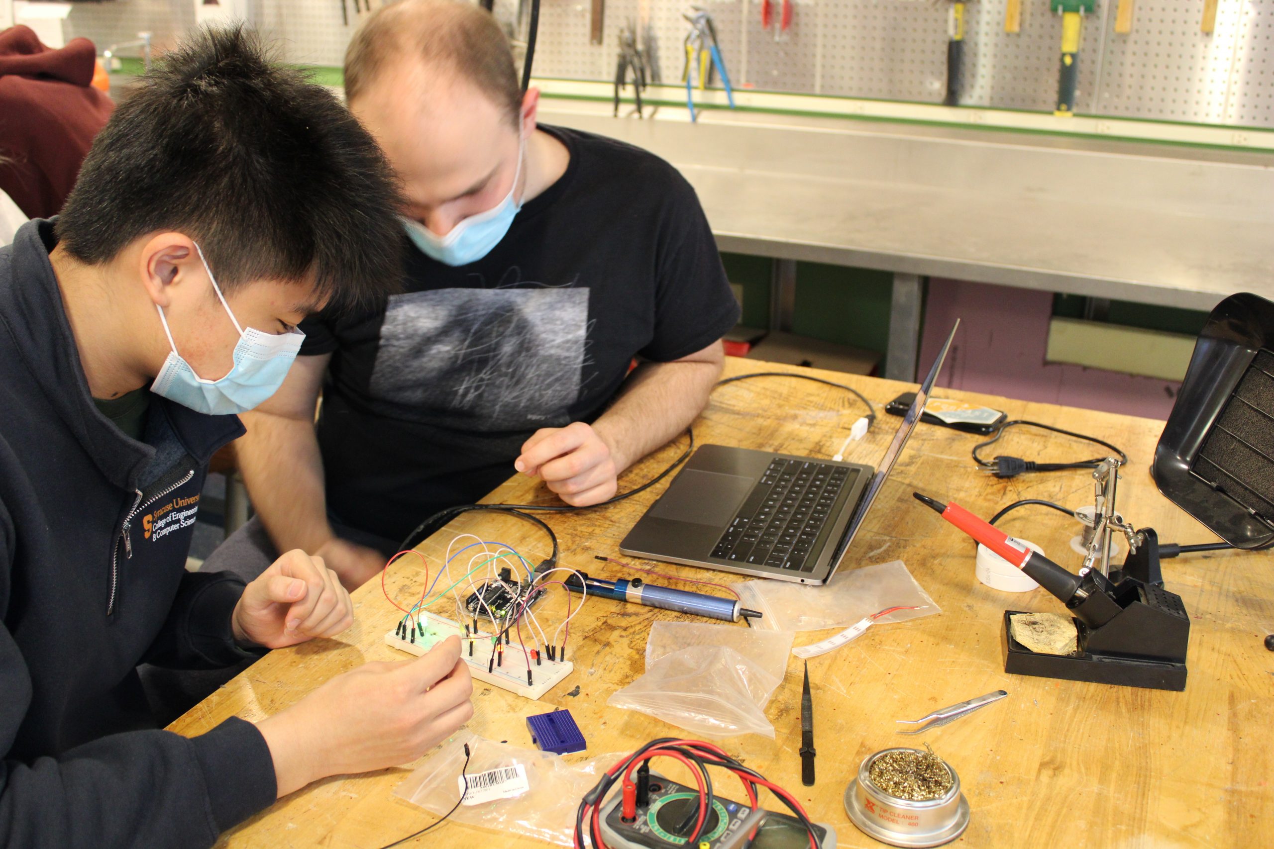 a close up from the Lutron Lighting Arduino and Soldering workshop, 2 students working on an arduino and breadboard, 1 holding wires