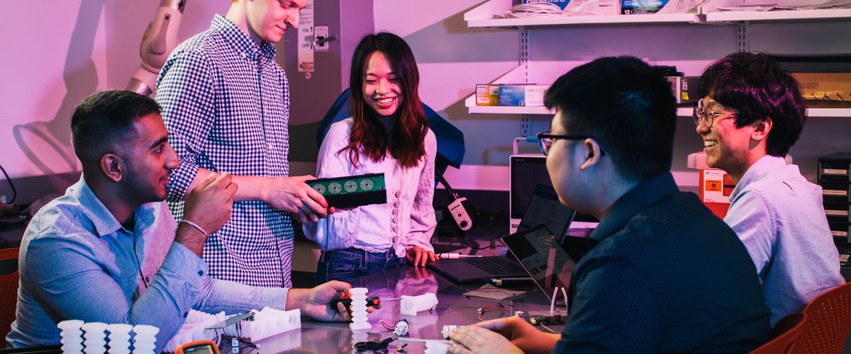 Group of Engineering students working together around a table in a lab setting