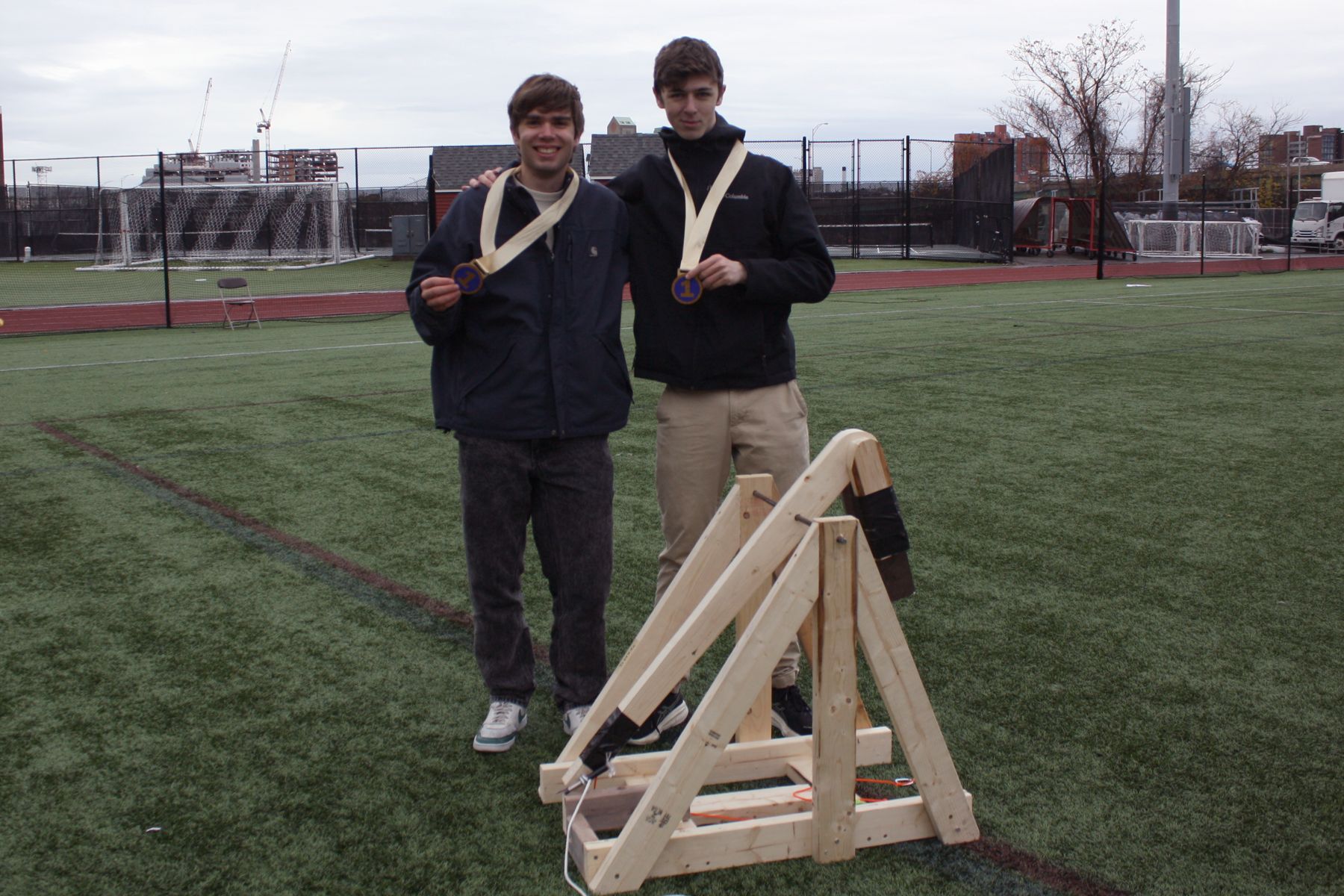 2 students standing next to their catapult with first place ribbons around their necks