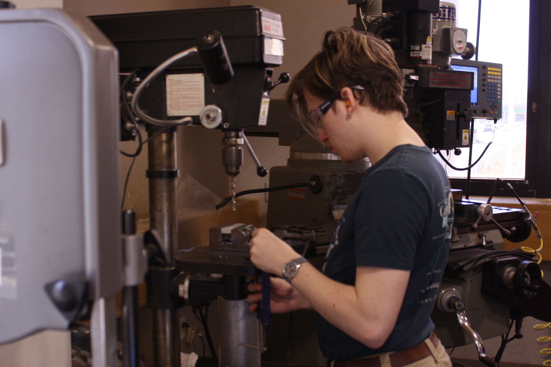 a student setting up his material in the vise to use the drill press
