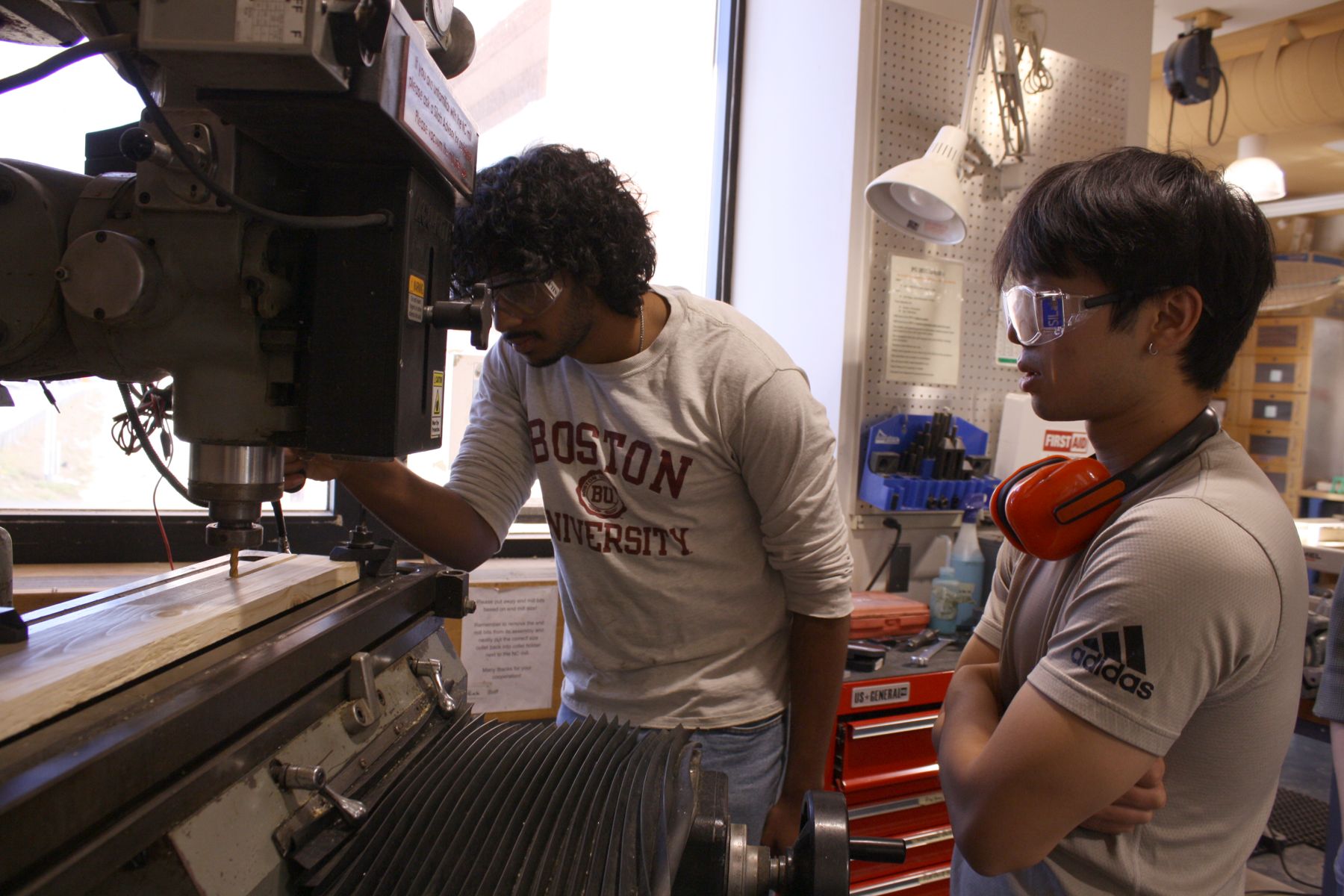2 students using the NC mill to mill out a slot in their board