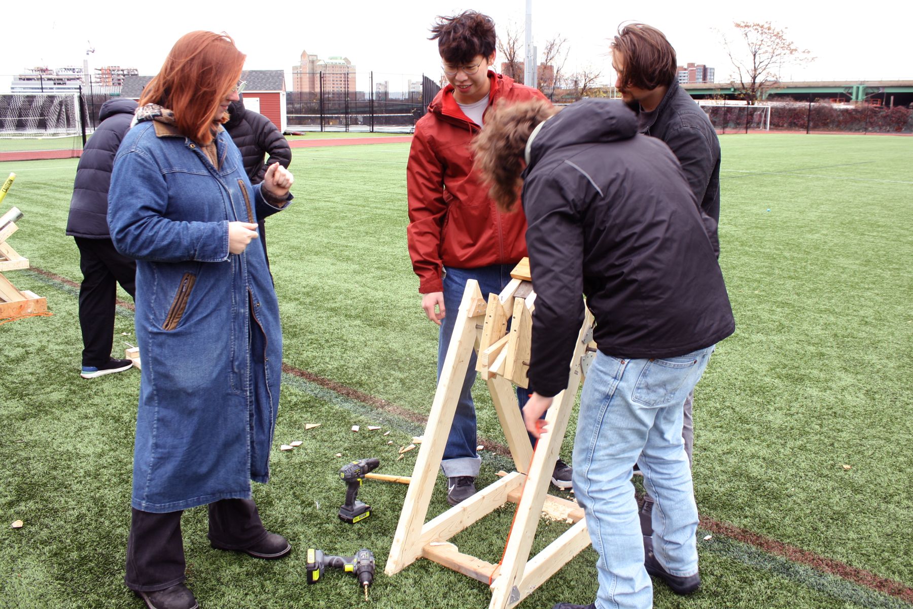3 students manipulating their catapult to demonstrate while K watches
