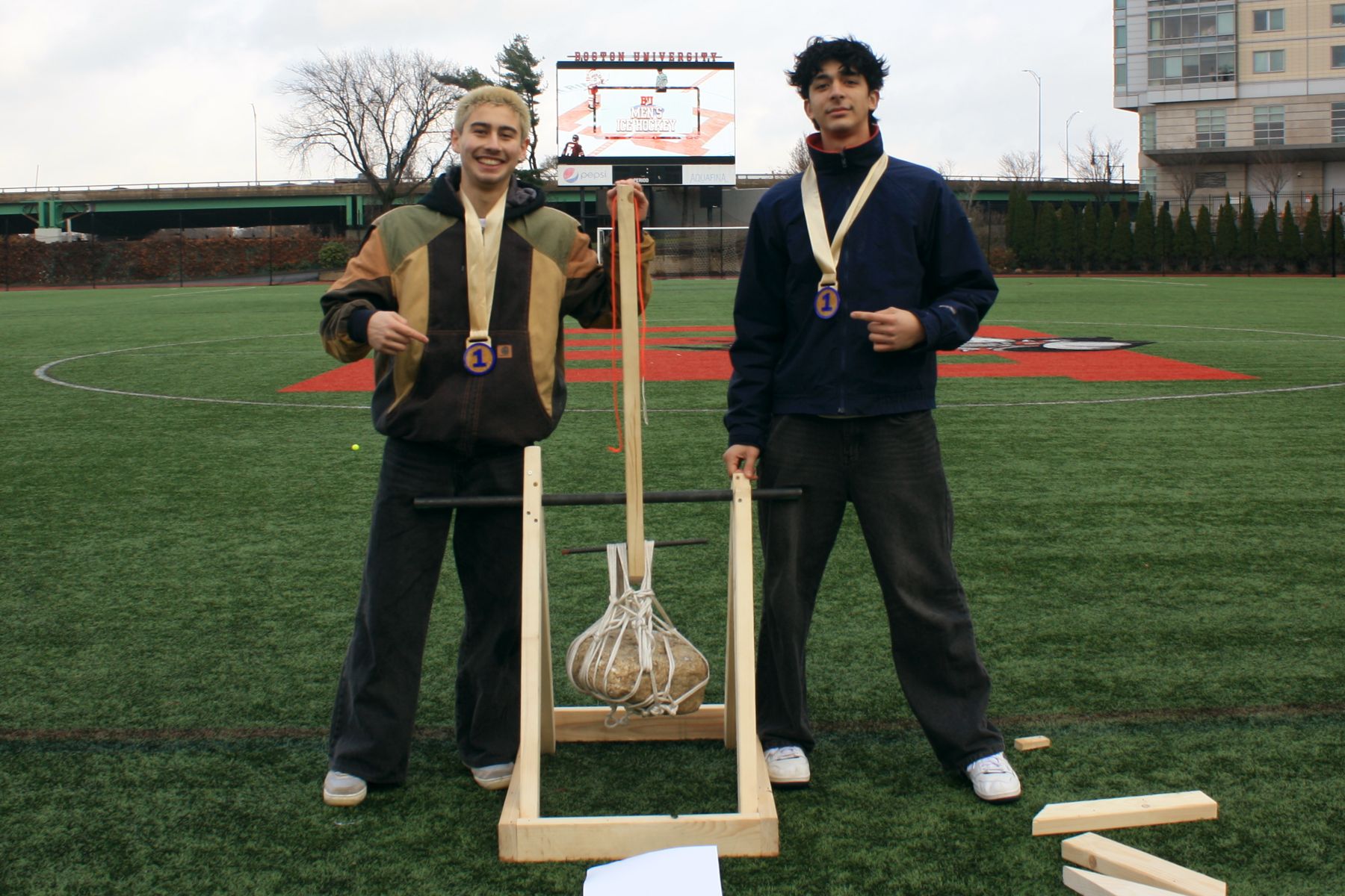 2 of the winning team standing with their catapult between them wearing first place medals