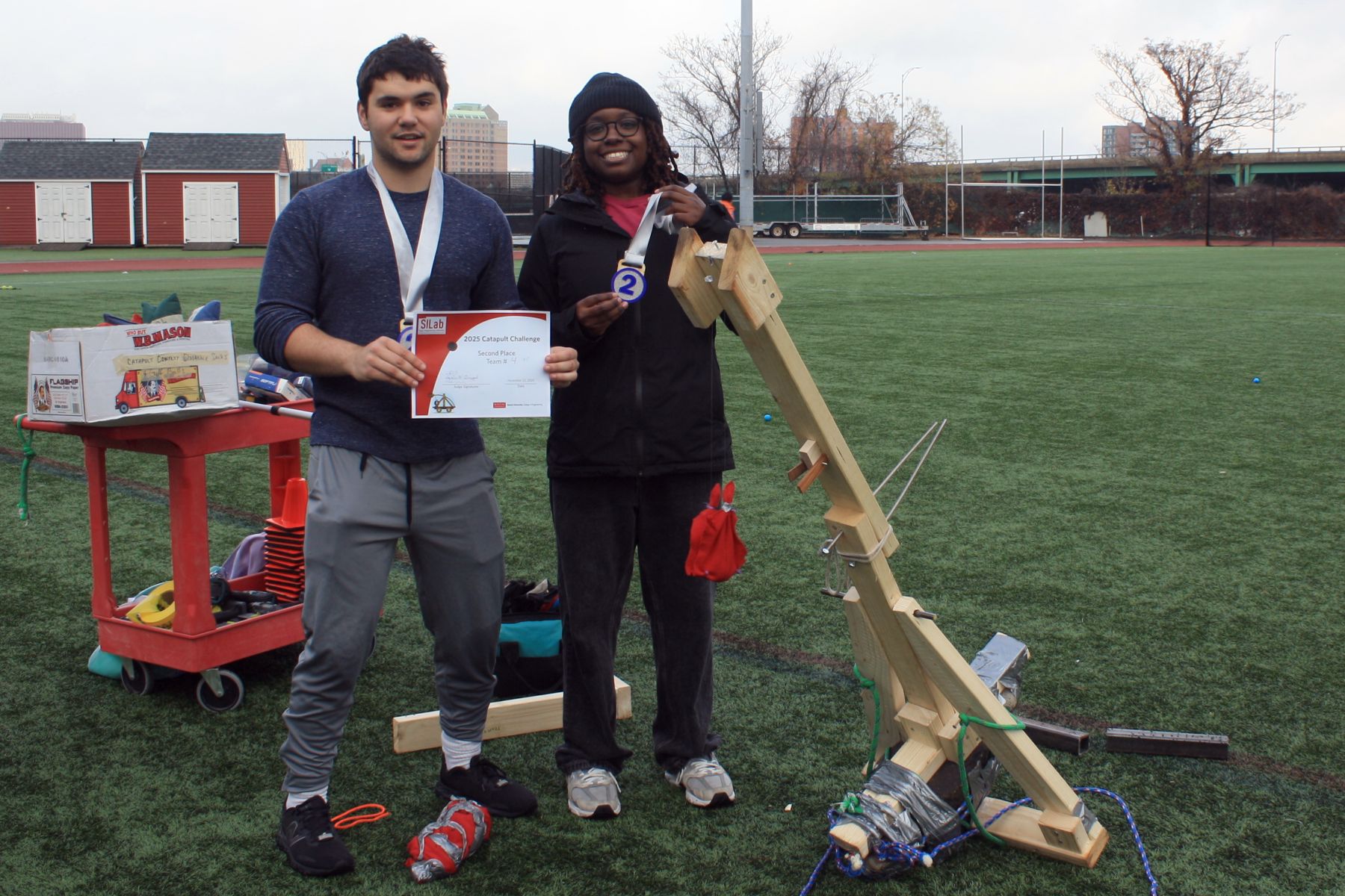 2 students with their catapult next to them wearing their 2nd place ribbons