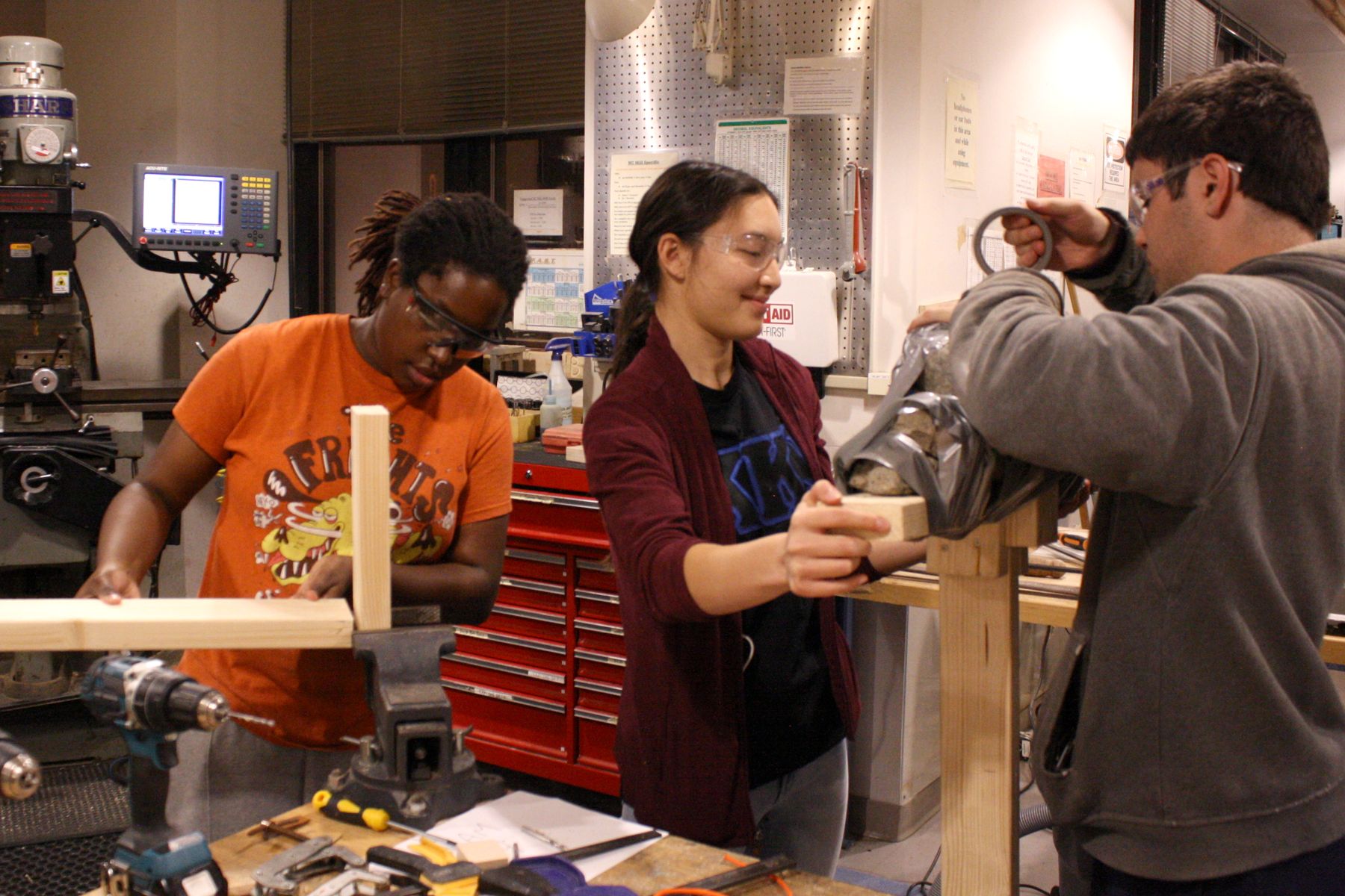 2 members of the team work to tape their rock weight in place while the 3rd member works on aligning their next board