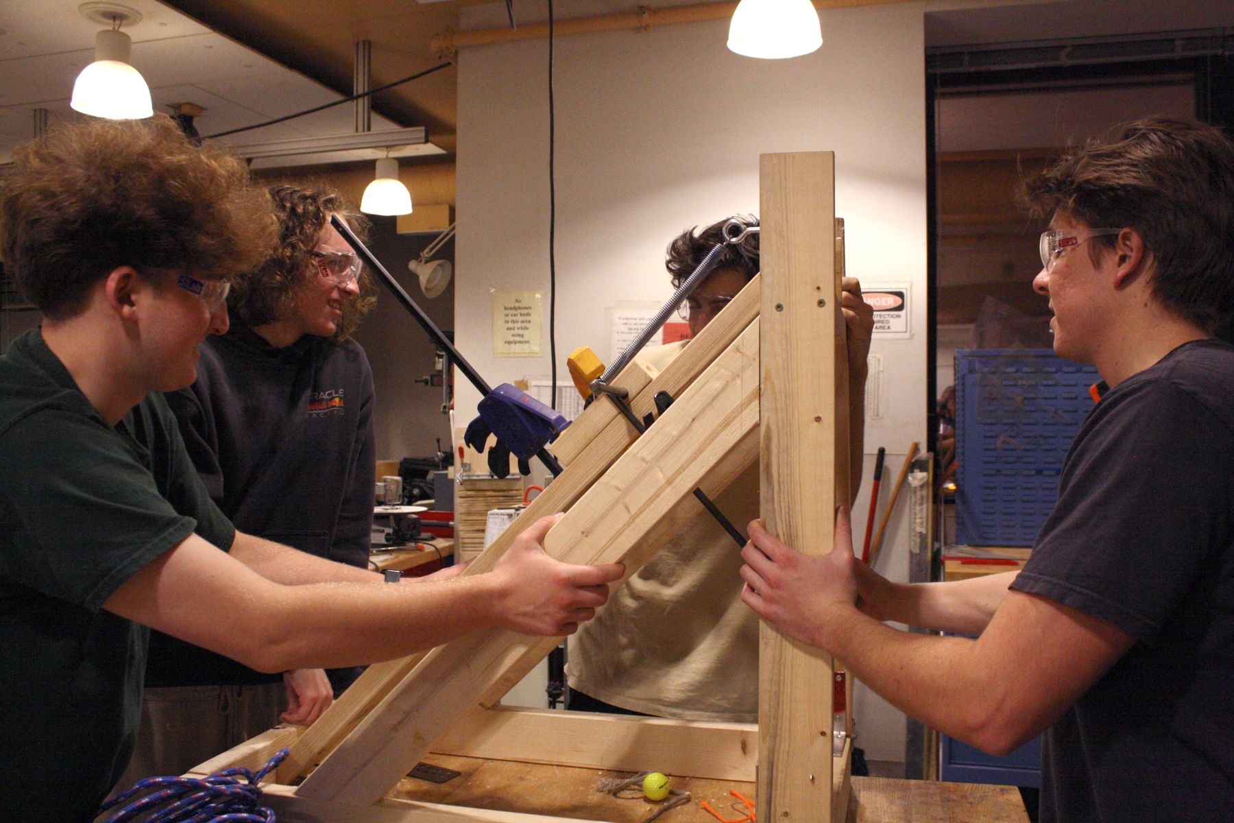 4 members of the team getting ready to pick up their catapult and bring it outside for stress testing