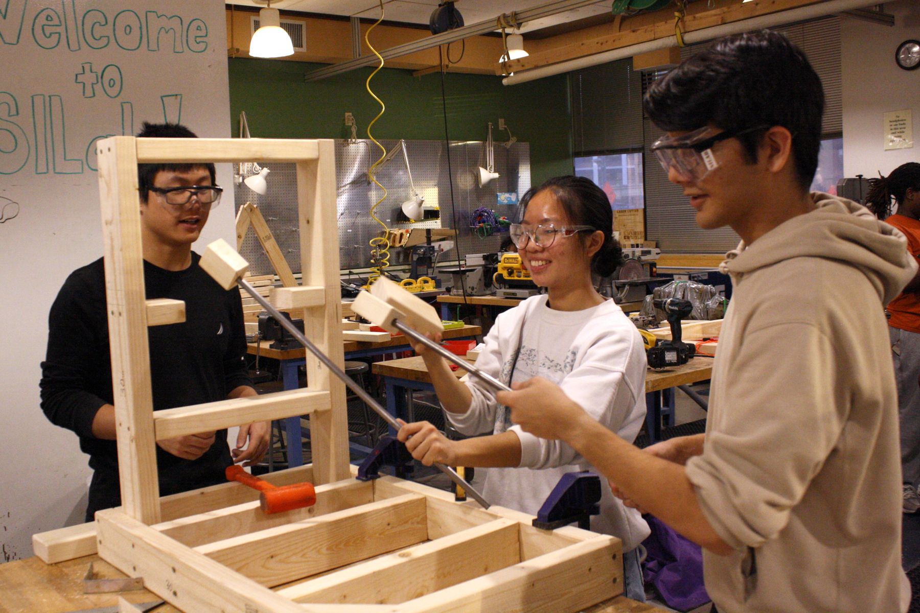 3 students working on adding in the cross beams for their catapult design