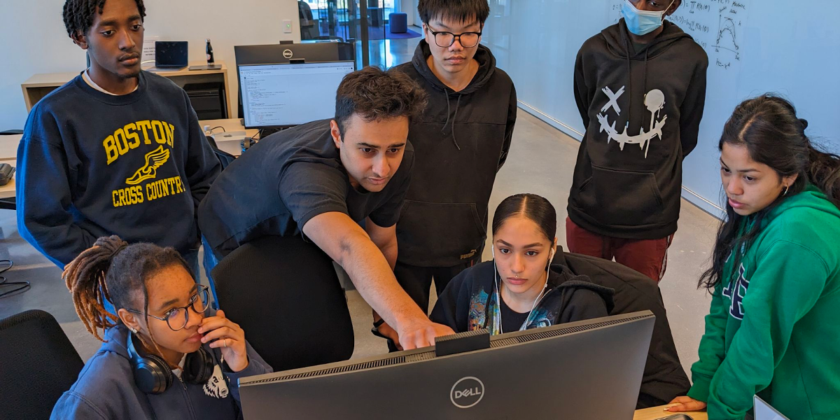 A group of software engineering students gather around a computer.