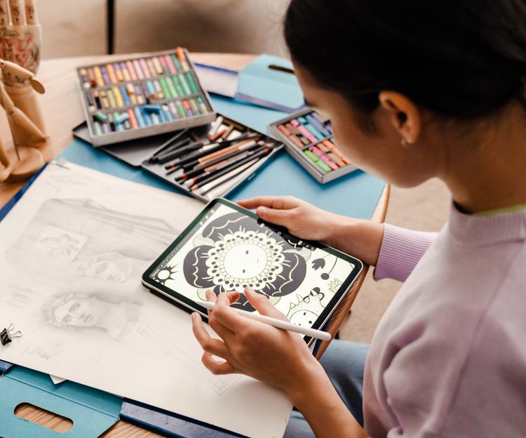 Back view of woman artist drawing on digital tablet while sitting in living room