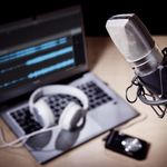 Podcast microphone, laptop computer camera and headphones on desk in recording studio