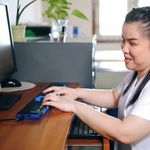 Asian woman with blindness disability using computer with refreshable braille display or braille terminal a technology assistive device for persons with visual impairment in workplace.